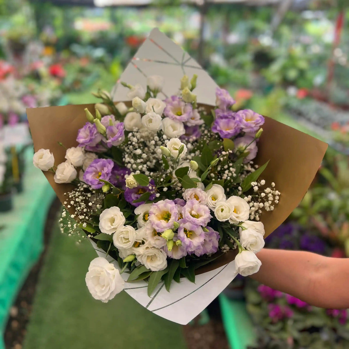 זר פרחים עם פרחים לבנים וסגולים עטוף